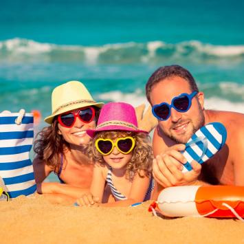 Happy family on the beach with colorful heart-shaped sunglasses.
