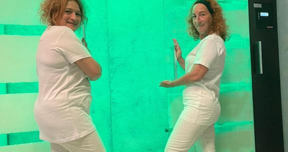 Deux personnes en blanc devant une pièce éclairée en vert.