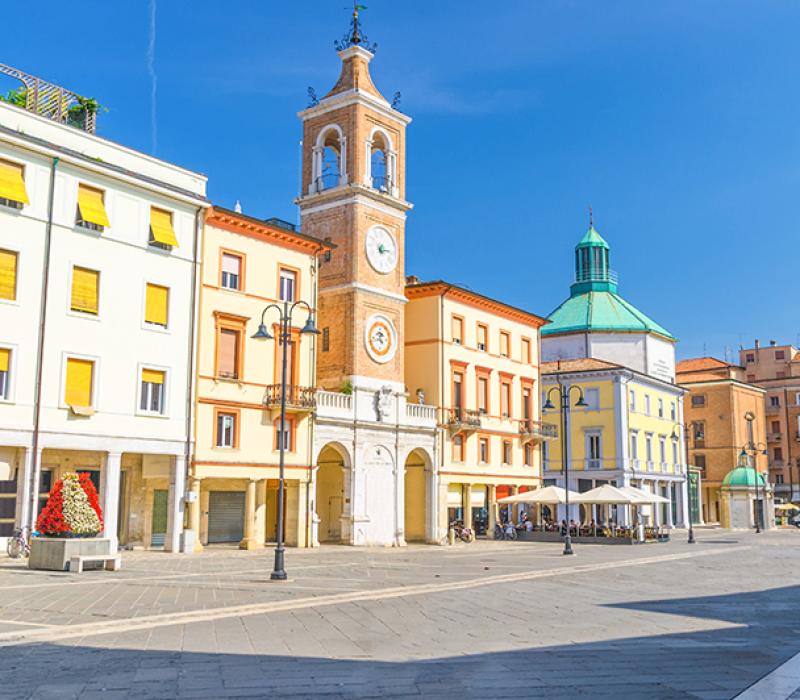 Torre dell'orologio al tramonto, luci soffuse, atmosfera serena e storica in città italiana.