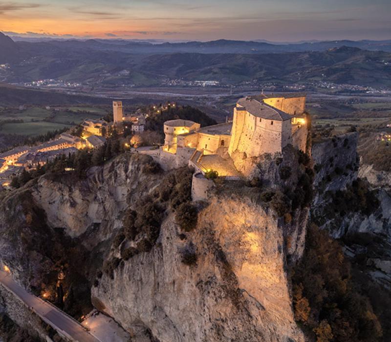 Maestoso castello illuminato al tramonto, su una scogliera imponente e suggestiva.