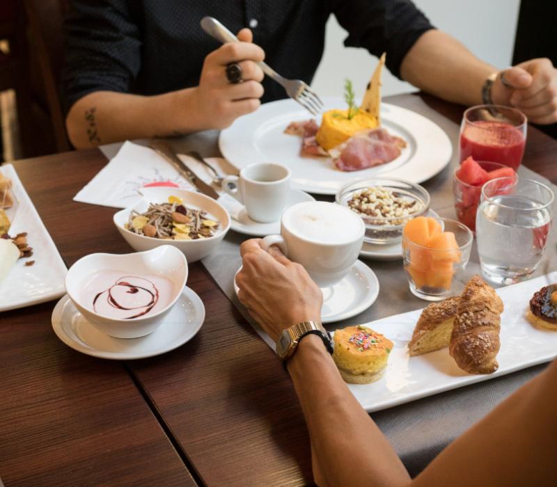 Petit-déjeuner élégant avec café, pâtisseries et fruits, ambiance intime et raffinée.