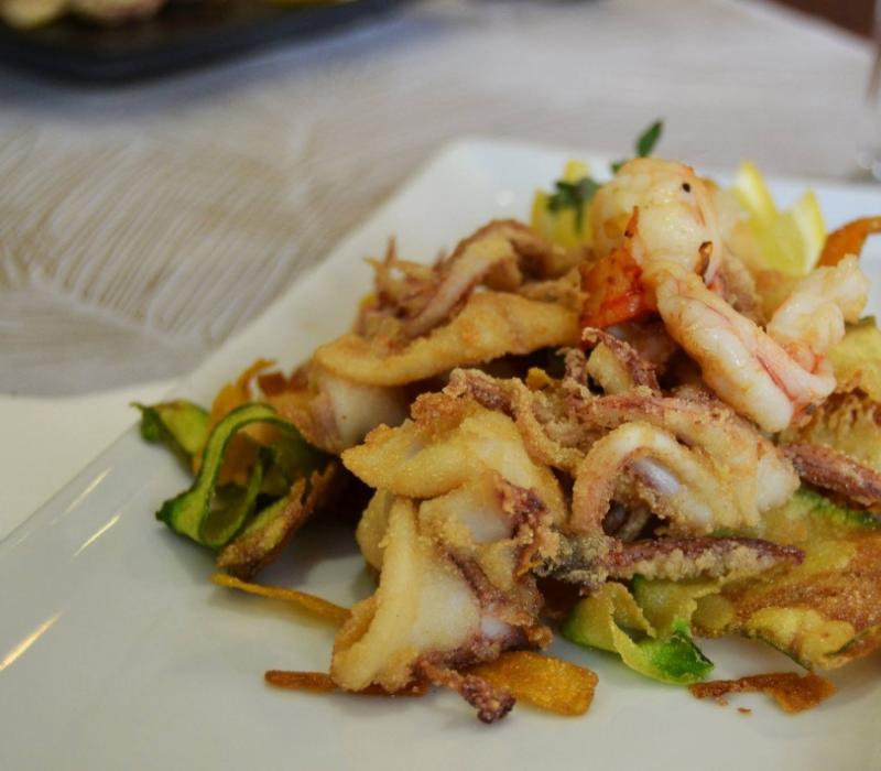 Delizioso fritto misto di mare con gamberi e calamari su un piatto elegante.