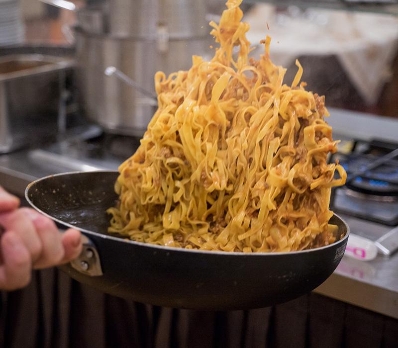 Pasta saltata in padella, calda e fumante, sembra deliziosa e invitante.