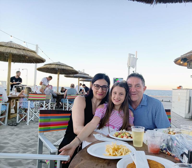 Famiglia felice al tramonto sulla spiaggia, sorrisi e cibo delizioso, atmosfera serena.
