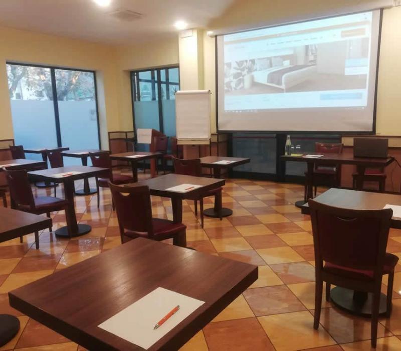 Aula luminosa, tavoli distanziati, proiettore acceso: atmosfera di apprendimento e concentrazione.
