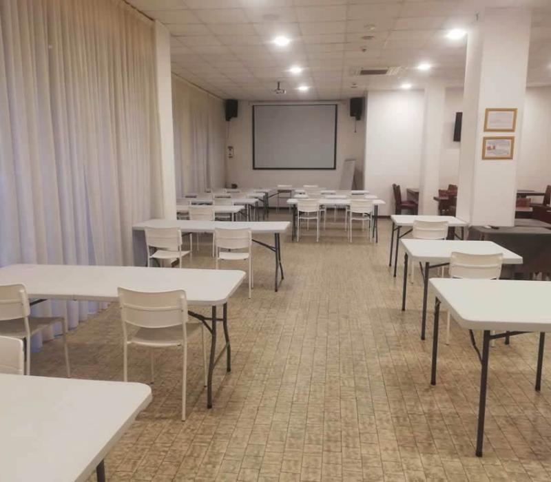Sala conferenze vuota, tavoli bianchi, atmosfera silenziosa e formale, attesa di un evento.